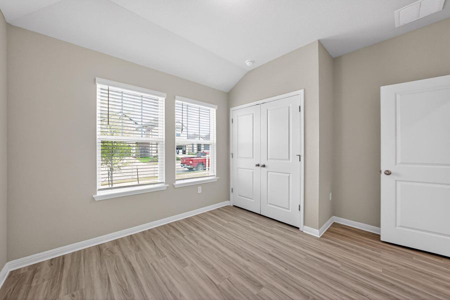 Unfurnished bedroom with lofted ceiling, light wood-style floors, and a closet