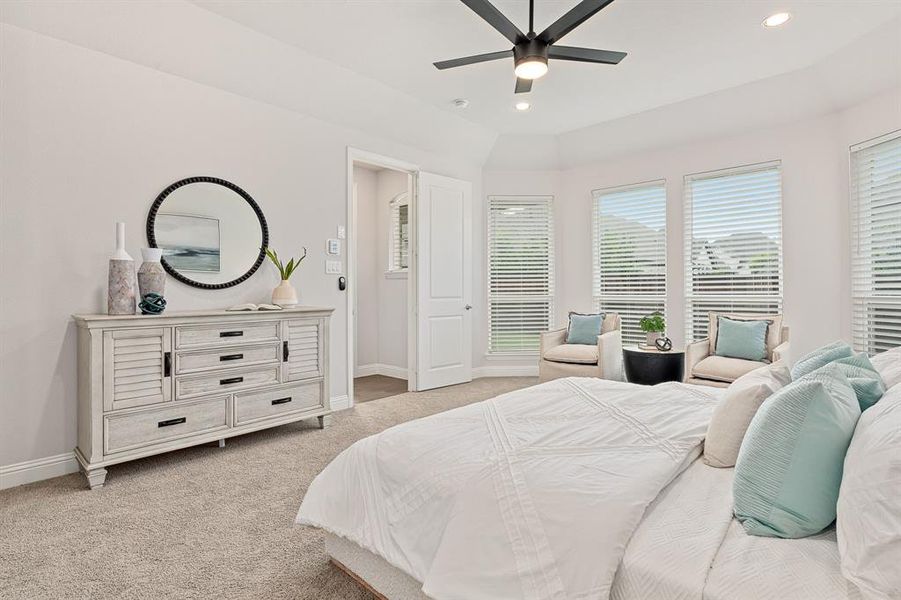 Spacious primary bedroom featuring bay windows and views of the backyard