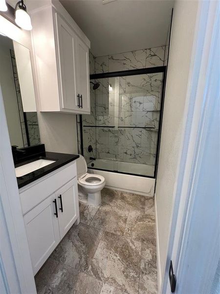 Bathroom with enclosed tub / shower combo, toilet, and vanity