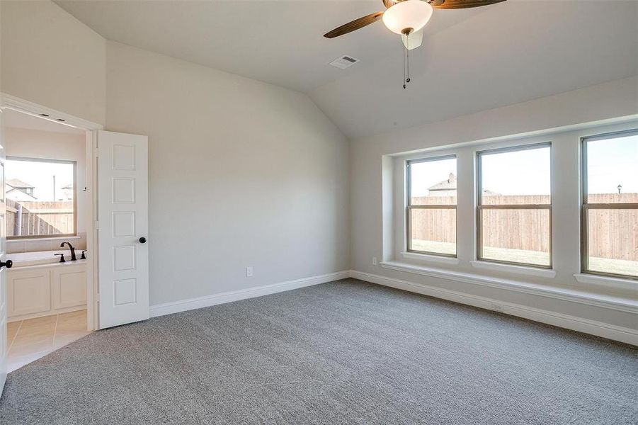 Spare room with ceiling fan, light colored carpet, a healthy amount of sunlight, and lofted ceiling