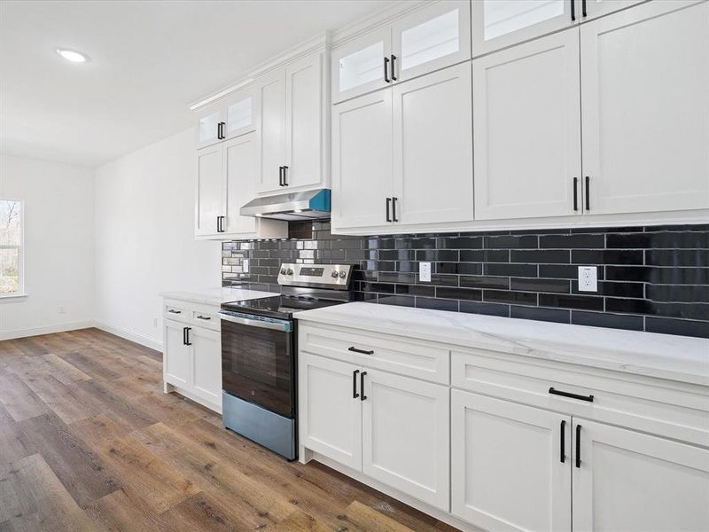 Kitchen featuring stainless steel range with electric cooktop, white cabinets, dark wood-style flooring, and glass fronted cabinets