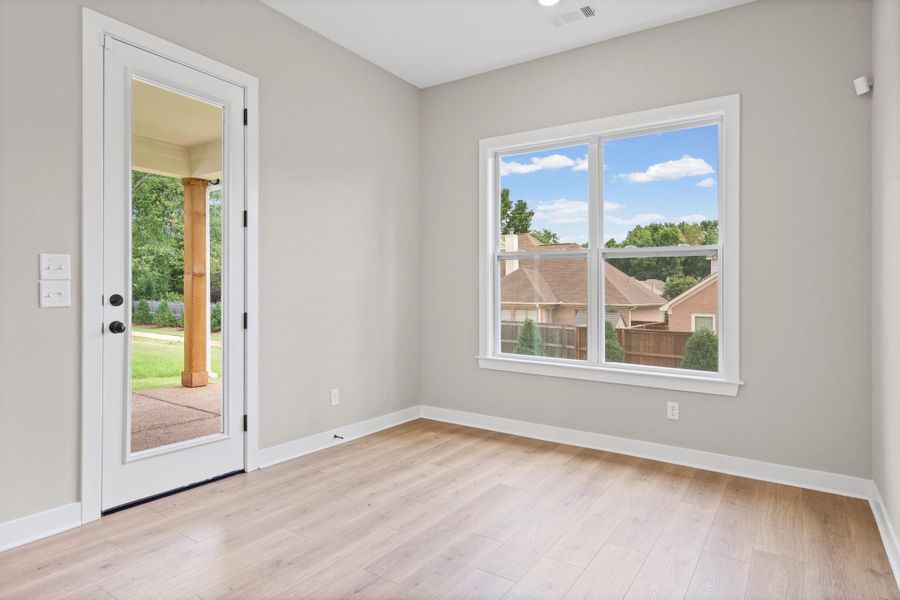 Light-filled interior space with wood-finish flooring, neutral wall tones, and white baseboards Light-filled interior space with wood-finish flooring, neutral wall tones, and white baseboards