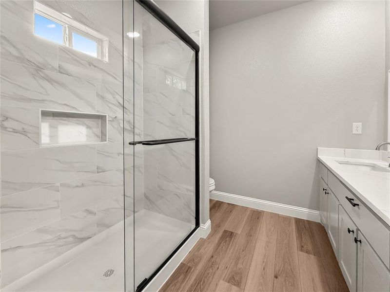 Spacious bathroom featuring a glass-enclosed shower with marble-look tile surround and an integrated shower niche