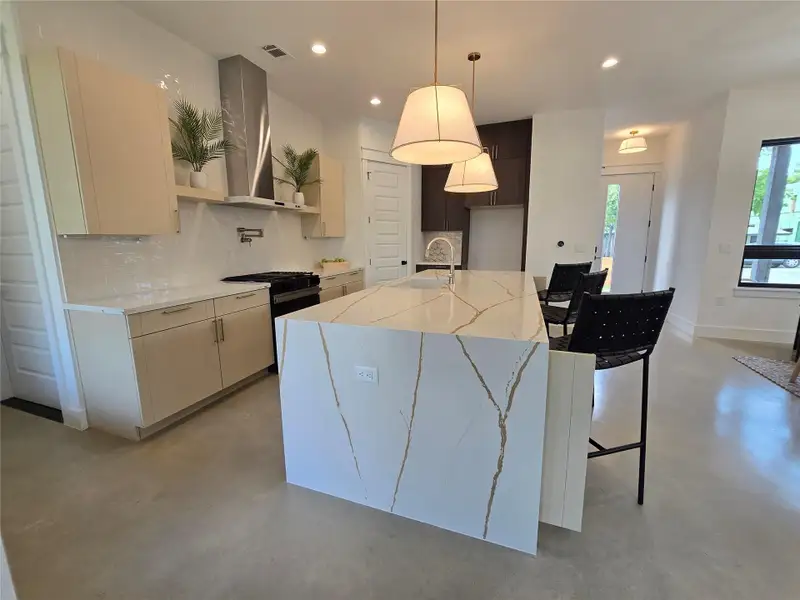 Kitchen featuring backsplash, a sink, finished concrete flooring, and range with gas stovetop Kitchen featuring backsplash, a sink, finished concrete flooring, and range with gas stovetop