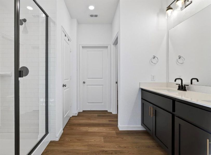 Bathroom with double vanity, dark wood-style flooring, a stall shower, and recessed lighting