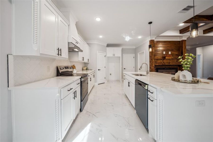 Bright kitchen featuring white cabinetry, a large center island with a sink, stainless steel appliances, a herringbone tile backsplash, and polished tile flooring