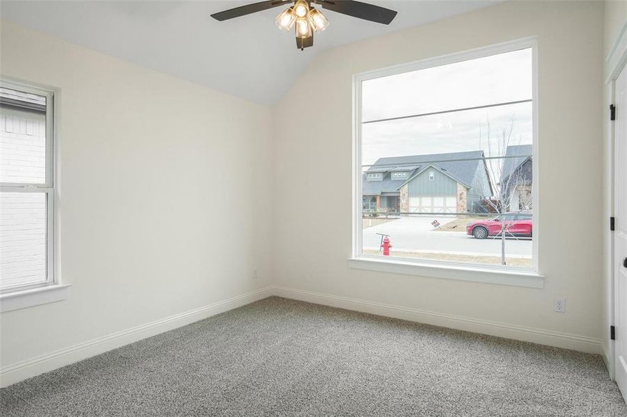 Carpeted empty room with ceiling fan and lofted ceiling