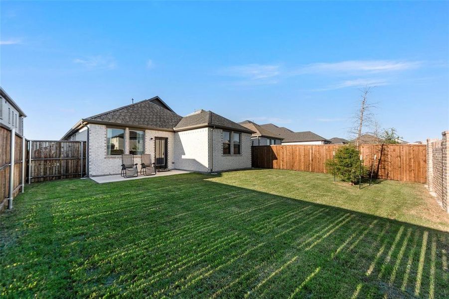 Rear view of house with brick siding, a fenced backyard, a patio area, and roof with shingles Rear view of house with brick siding, a fenced backyard, a patio area, and roof with shingles