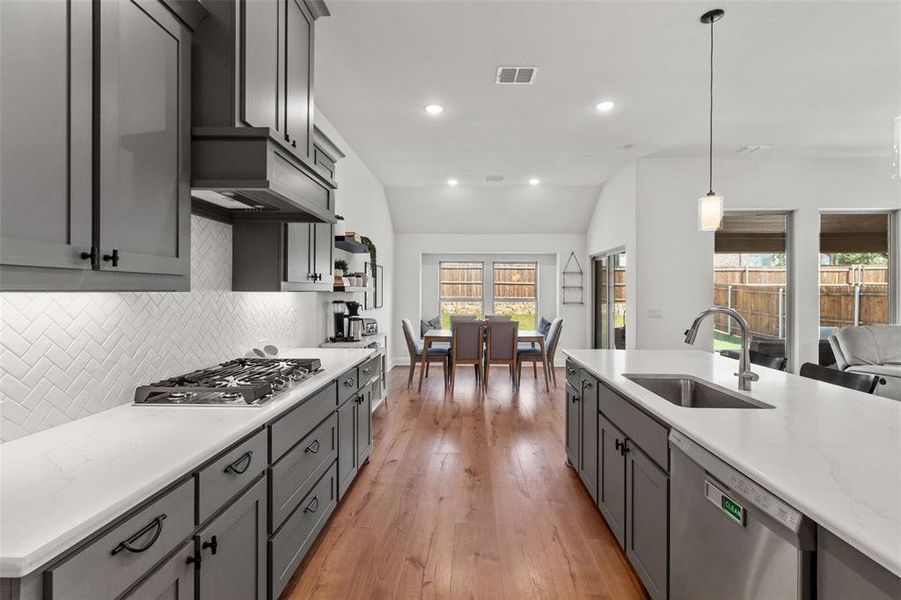 Kitchen with hanging light fixtures, appliances with stainless steel finishes, recessed lighting, tasteful backsplash, and light wood-style floors