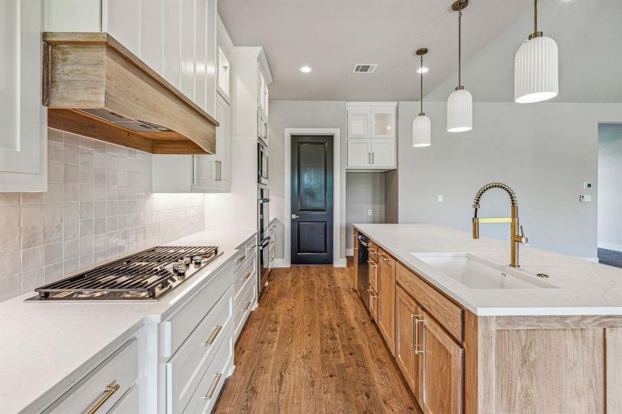 Kitchen featuring hardwood / wood-style flooring, sink, white cabinets, and backsplash