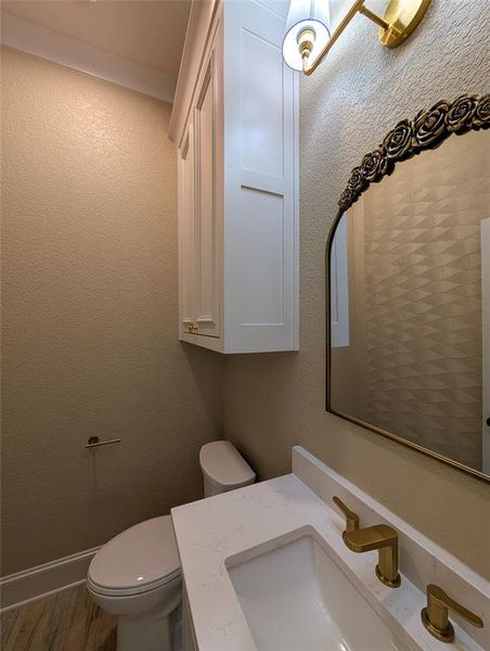 Half bathroom with a textured wall, vanity, and wood finished floors