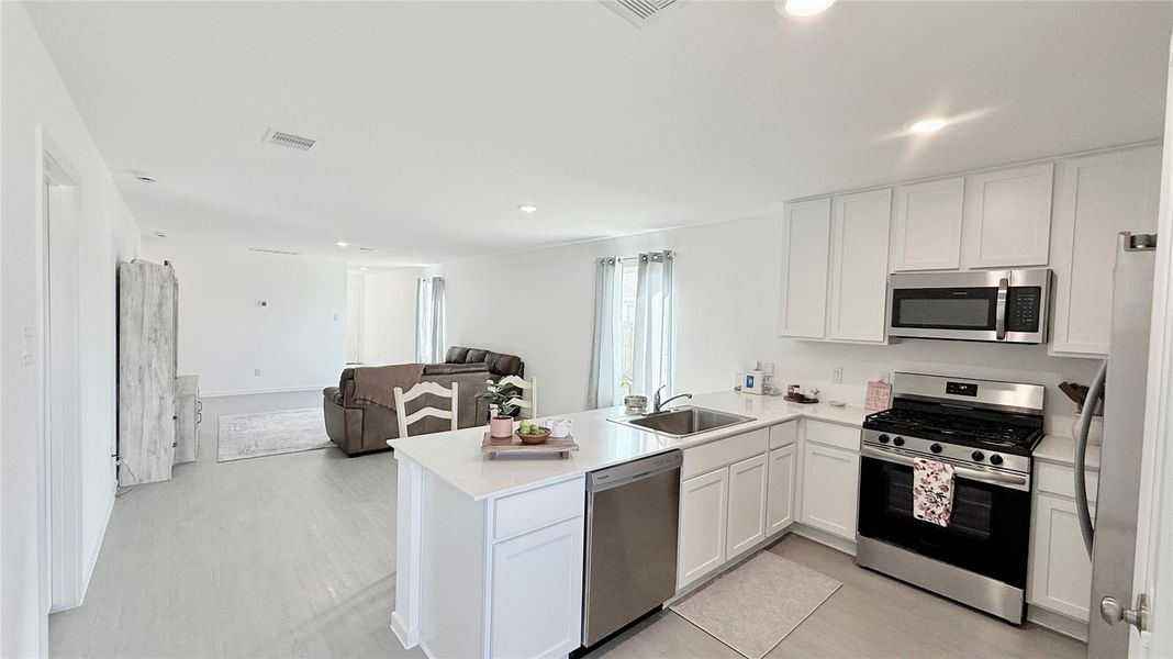 This view from the back of the house showcases the open flow from the kitchen to the dining area and family room, leading toward the separate private front entrance. This view from the back of the house showcases the open flow from the kitchen to the dining area and family room, leading toward the separate private front entrance.