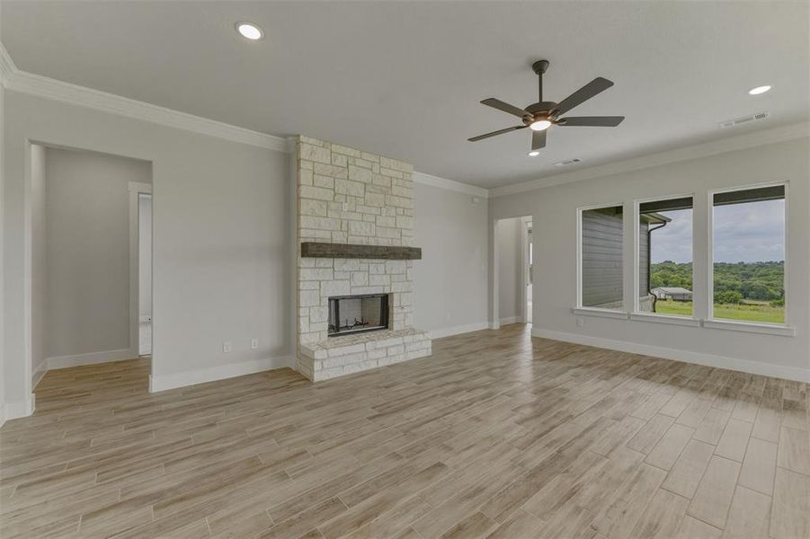 Expansive living area featuring a stacked stone fireplace with a substantial wood mantel Expansive living area featuring a stacked stone fireplace with a substantial wood mantel