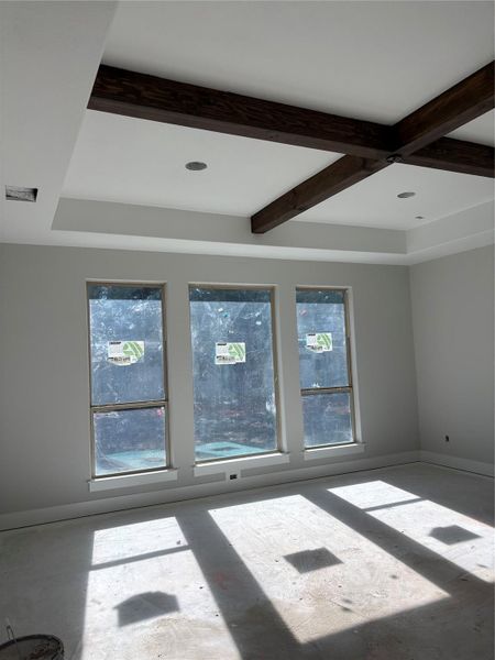 Spare room featuring coffered ceiling, beam ceiling, and plenty of natural light