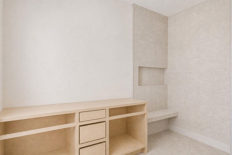 Built-in light wood cabinetry with open shelving and drawers, complemented by textured wall paneling featuring a recessed niche and integrated bench seating