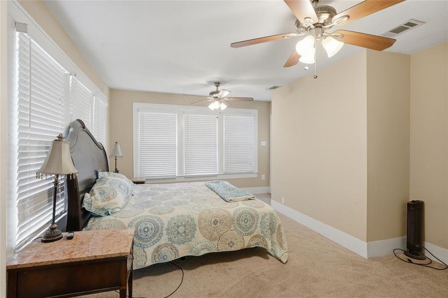 Carpeted interior space featuring multiple windows with blinds, two ceiling fans with integrated lighting, and neutral wall tones