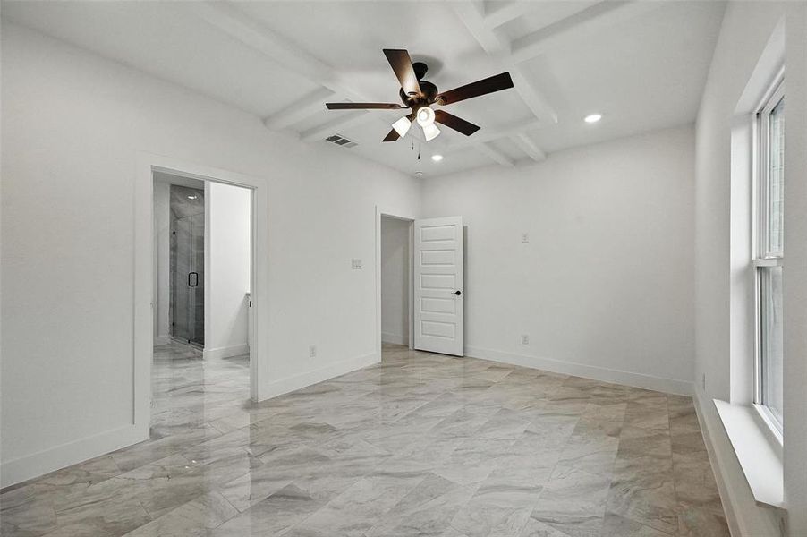 Unfurnished bedroom featuring recessed lighting, coffered ceiling, beam ceiling, light marble finish floors, and ensuite bath