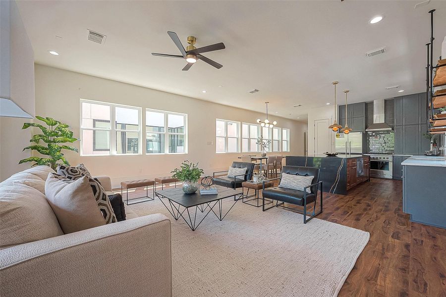 Open-concept living space with high ceilings, hardwood floors, modern kitchen with stainless steel appliances, ample natural light from large windows, and a cohesive neutral color palette. Open-concept living space with high ceilings, hardwood floors, modern kitchen with stainless steel appliances, ample natural light from large windows, and a cohesive neutral color palette.