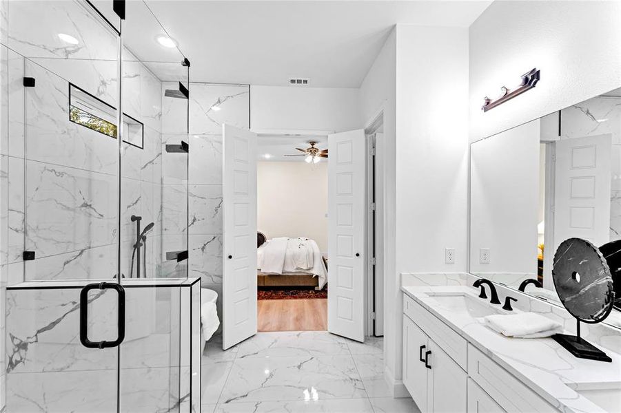 Bathroom featuring vanity, ceiling fan, and a shower with shower door