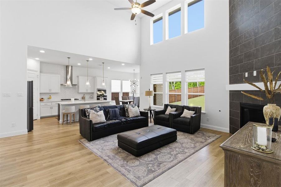 Open-concept living space featuring high ceilings, wood-finish flooring, and a contemporary fireplace with dark tile surround