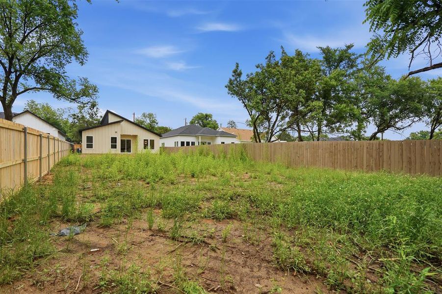 Expansive rear yard featuring a newly installed privacy fence, ample green space, and mature perimeter trees