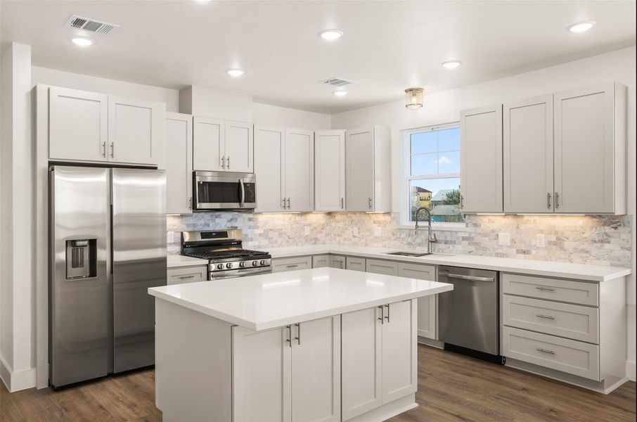 The kitchen offers 42" cabinetry, quartz countertops, large island, tile backsplash, walk-in pantry, and a full appliance package including gas cooktop and built-in oven The kitchen offers 42" cabinetry, quartz countertops, large island, tile backsplash, walk-in pantry, and a full appliance package including gas cooktop and built-in oven