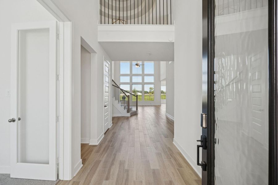 Let’s step inside this impressive two-story home, defined by a modern dark-framed glass door and wood-look plank flooring that flows seamlessly throughout the main living areas.