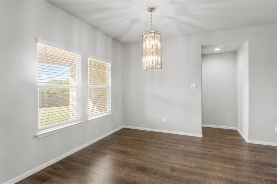 Empty room featuring dark wood-type flooring and an inviting chandelier