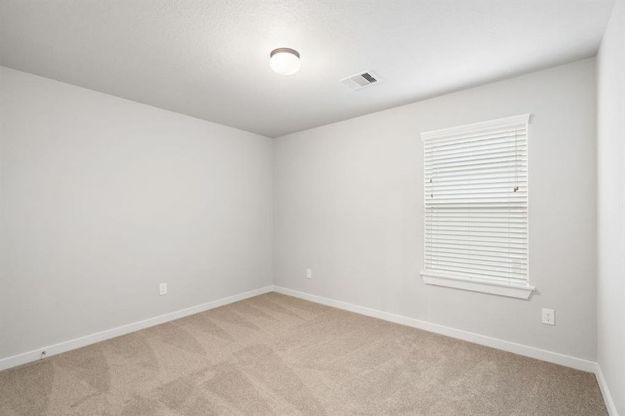 Generously sized secondary bedrooms featuring spacious closets, soft and inviting carpeting underfoot, large windows allowing plenty of natural light. Sample photo of completed home with similar floor plan. As-built interior colors and selections may vary.