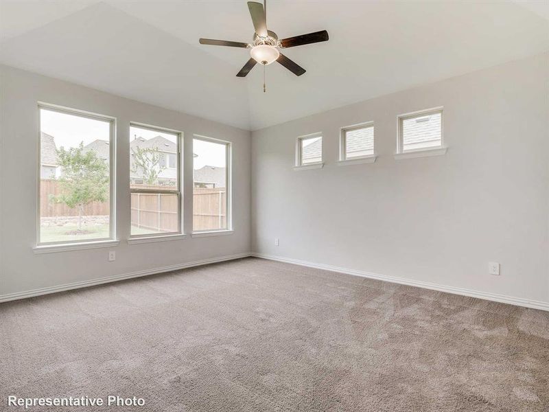 The property features a spacious room with vaulted ceilings, a ceiling fan, and ample natural light from several windows