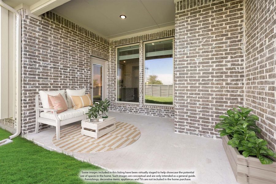 Covered brick patio with white outdoor sofa, coffee table, round rug, and potted plants near sliding glass door Covered brick patio with white outdoor sofa, coffee table, round rug, and potted plants near sliding glass door