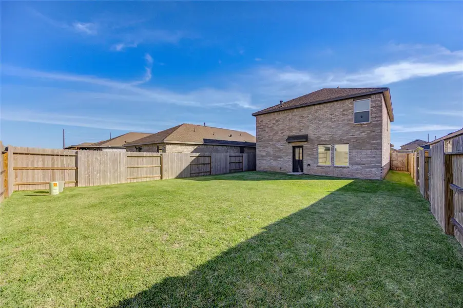Spacious fenced backyard with well-maintained lawn, perfect for outdoor activities. The brick home offers privacy and ample natural light.