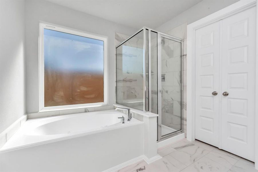 This additional view of the primary bath features a walk-in shower with the tile surround and separate garden tub perfect for soaking after a long day. Sample photo of completed home with similar floor plan. As-built interior colors and selections may vary.