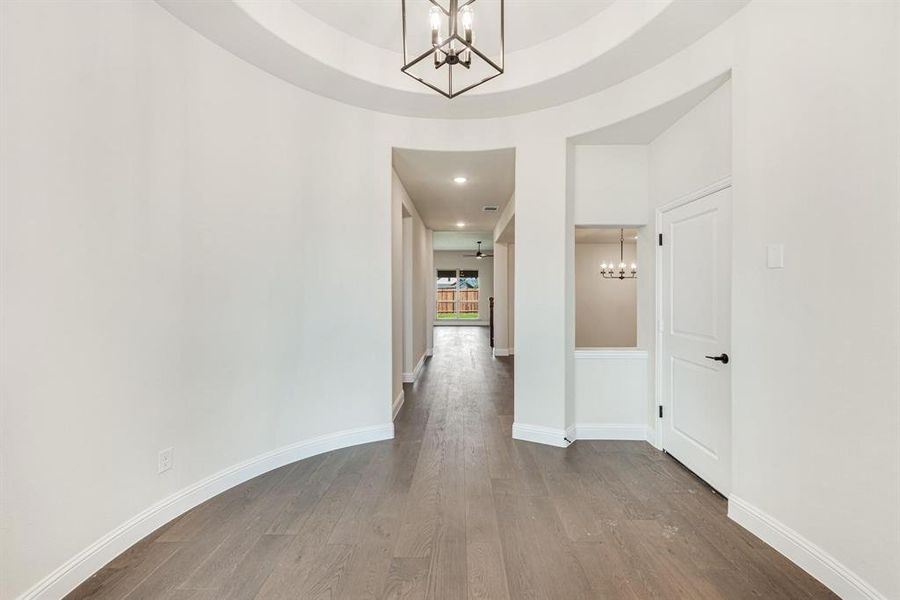 Hallway with a chandelier and dark wood-style flooring Hallway with a chandelier and dark wood-style flooring