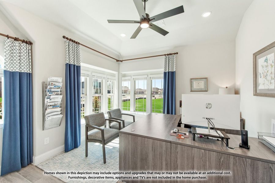 Home office with wood desk, ceiling fan, blue curtains, and large windows with backyard view
