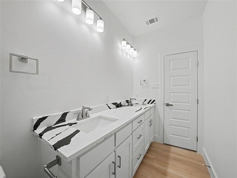 Double vanity with modern white cabinetry and contrasting black and white patterned countertops Double vanity with modern white cabinetry and contrasting black and white patterned countertops
