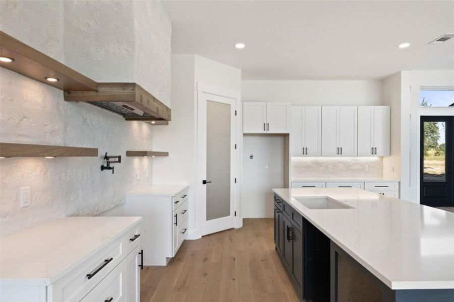 A contemporary kitchen showcasing light wood flooring and bright white cabinetry. A contemporary kitchen showcasing light wood flooring and bright white cabinetry.