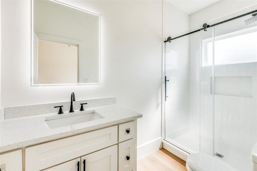 Bathroom with wood-type flooring, vanity, toilet, and an enclosed shower