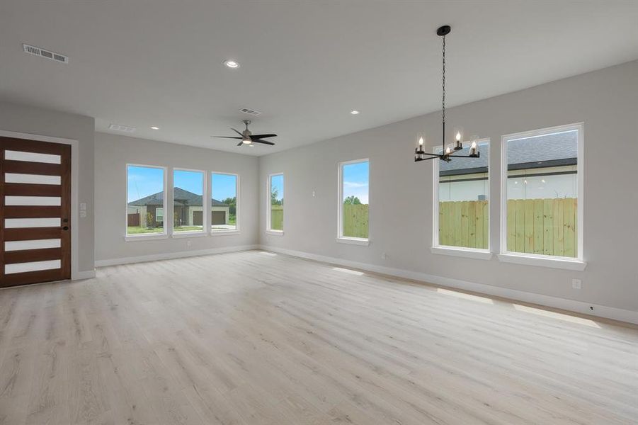 Unfurnished living room with baseboards, a chandelier, light wood finished floors, recessed lighting, and ceiling fan