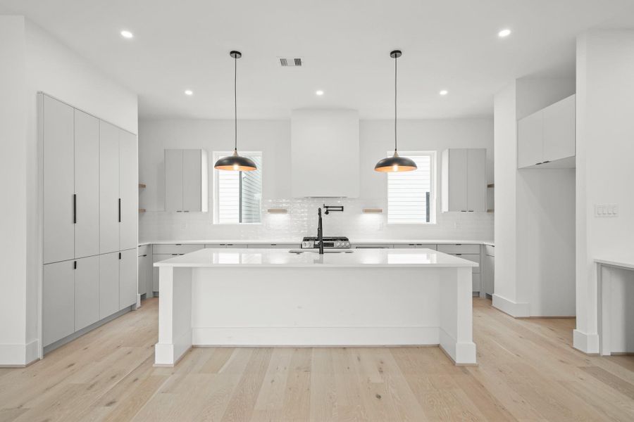Surrounded by shelves with under cabinet lighting and soft close doors and drawers, this gorgeous kitchen includes quartz counter tops, hardwood floors and the large island with breakfast bar seating.