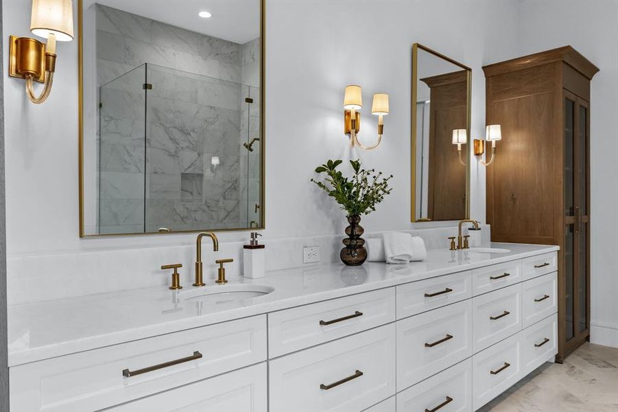 Bathroom featuring vanity with extensive cabinet space, an enclosed shower, dual sinks, and tile flooring