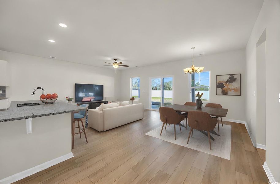 Dining room with baseboards, light wood finished floors, recessed lighting, and ceiling fan with notable chandelier