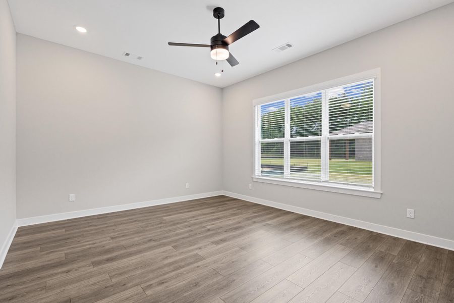 Spacious interior room featuring wood-finish flooring, a large multi-pane window with white blinds, a ceiling fan with integrated lighting, and recessed ceiling lights Spacious interior room featuring wood-finish flooring, a large multi-pane window with white blinds, a ceiling fan with integrated lighting, and recessed ceiling lights