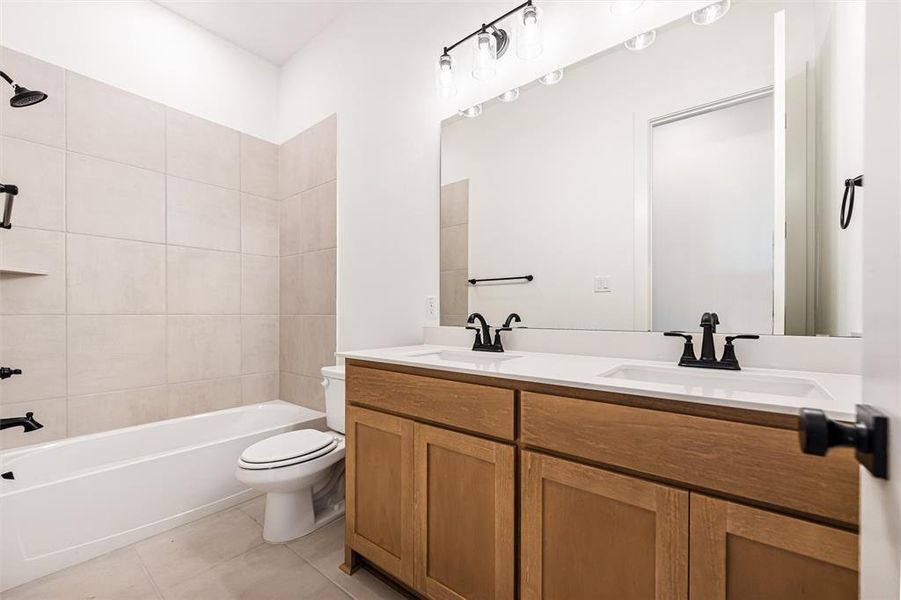 Full bath with double vanity, shower / bathtub combination, and light tile patterned floors