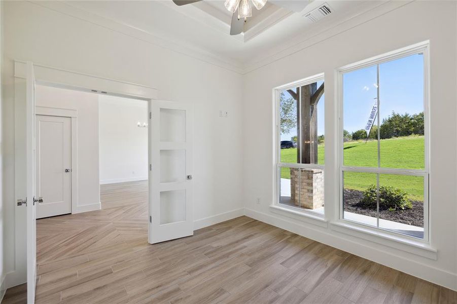 Spare room featuring light wood-type flooring, ceiling fan, and ornamental molding