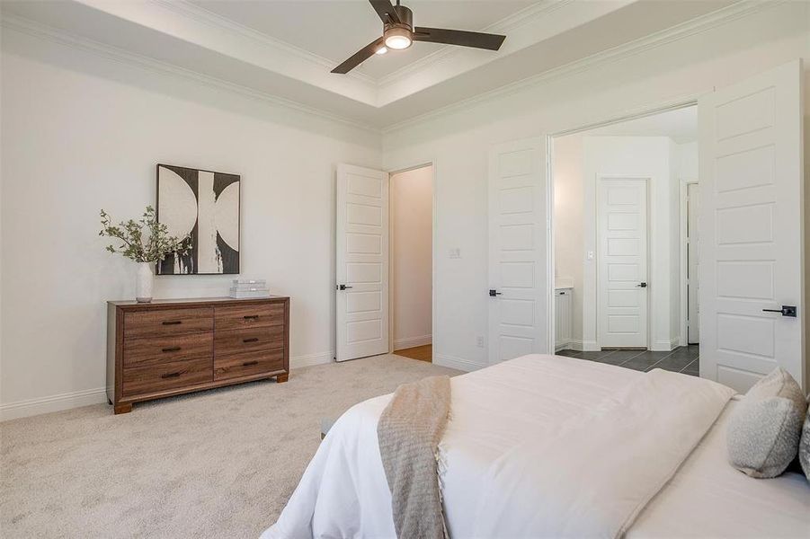 Bedroom featuring ornamental molding, a raised ceiling, carpet flooring, and ceiling fan