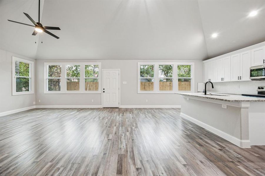 Kitchen with white cabinets, light wood finished floors, decorative backsplash, stainless steel appliances, and recessed lighting