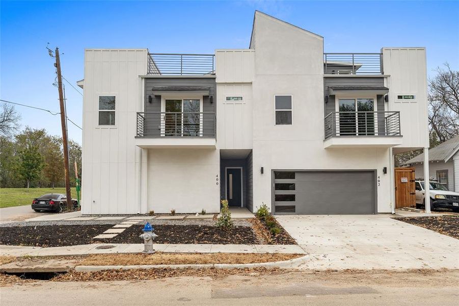 Modern home featuring a balcony, board and batten siding, concrete driveway, and a garage Modern home featuring a balcony, board and batten siding, concrete driveway, and a garage