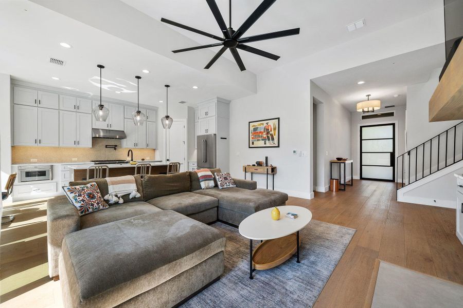 Living room with recessed lighting, light wood-style flooring, ceiling fan, and stairway