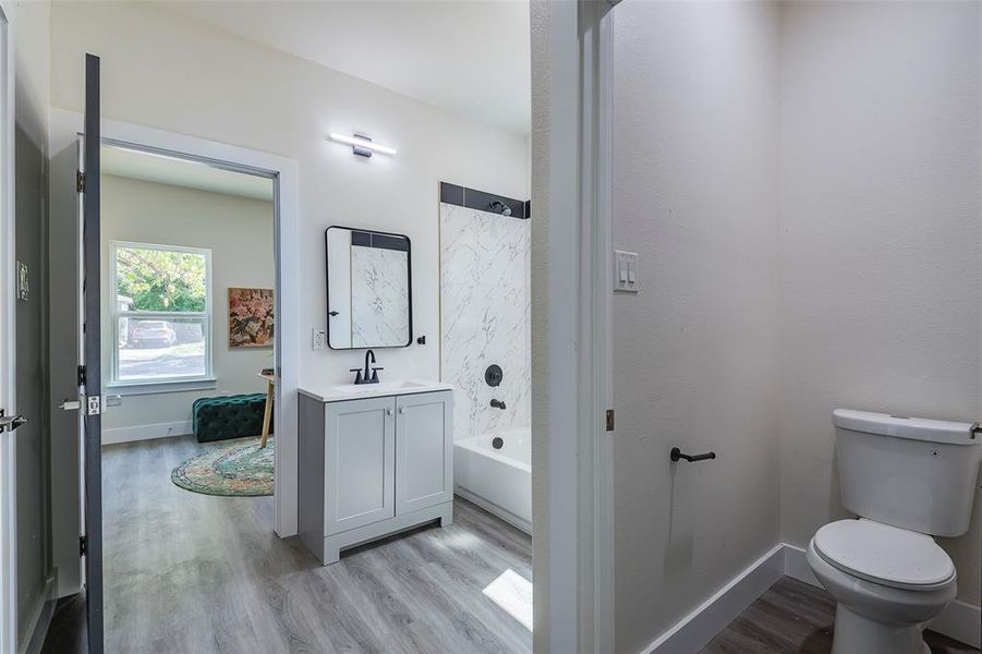 Full bathroom with hardwood / wood-style floors, washtub / shower combination, toilet, and vanity